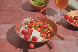 a bowl of rice, tomatoes, and lettuce on a table
