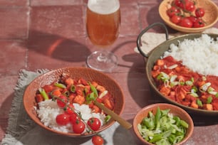 a table topped with bowls of food and a glass of beer