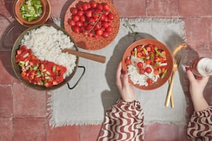 two bowls of rice, tomatoes, and broccoli on a table