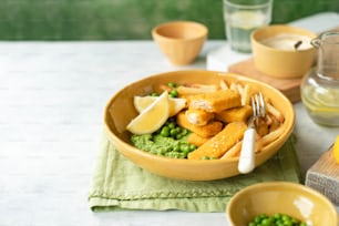 a bowl of food with peas and lemon wedges