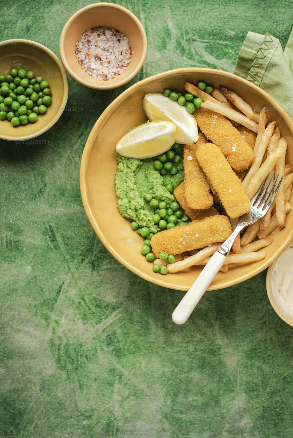 a bowl of food with peas, peas, lemon wedges and peas