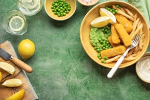 a bowl filled with fish and peas next to lemons