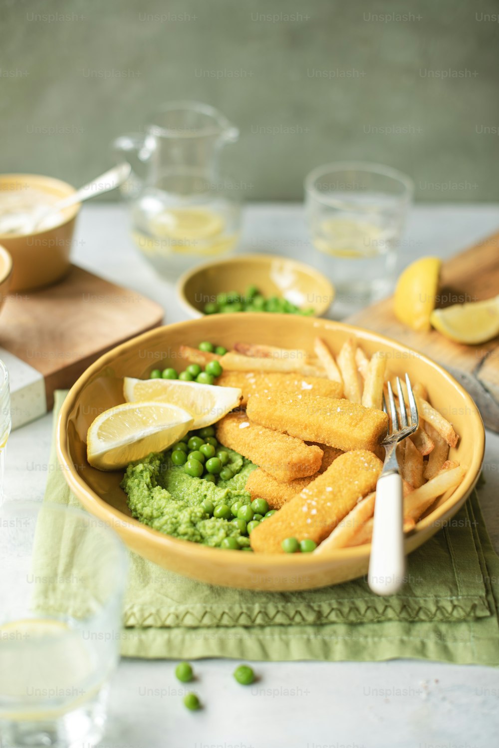 a bowl of food with peas and lemon wedges