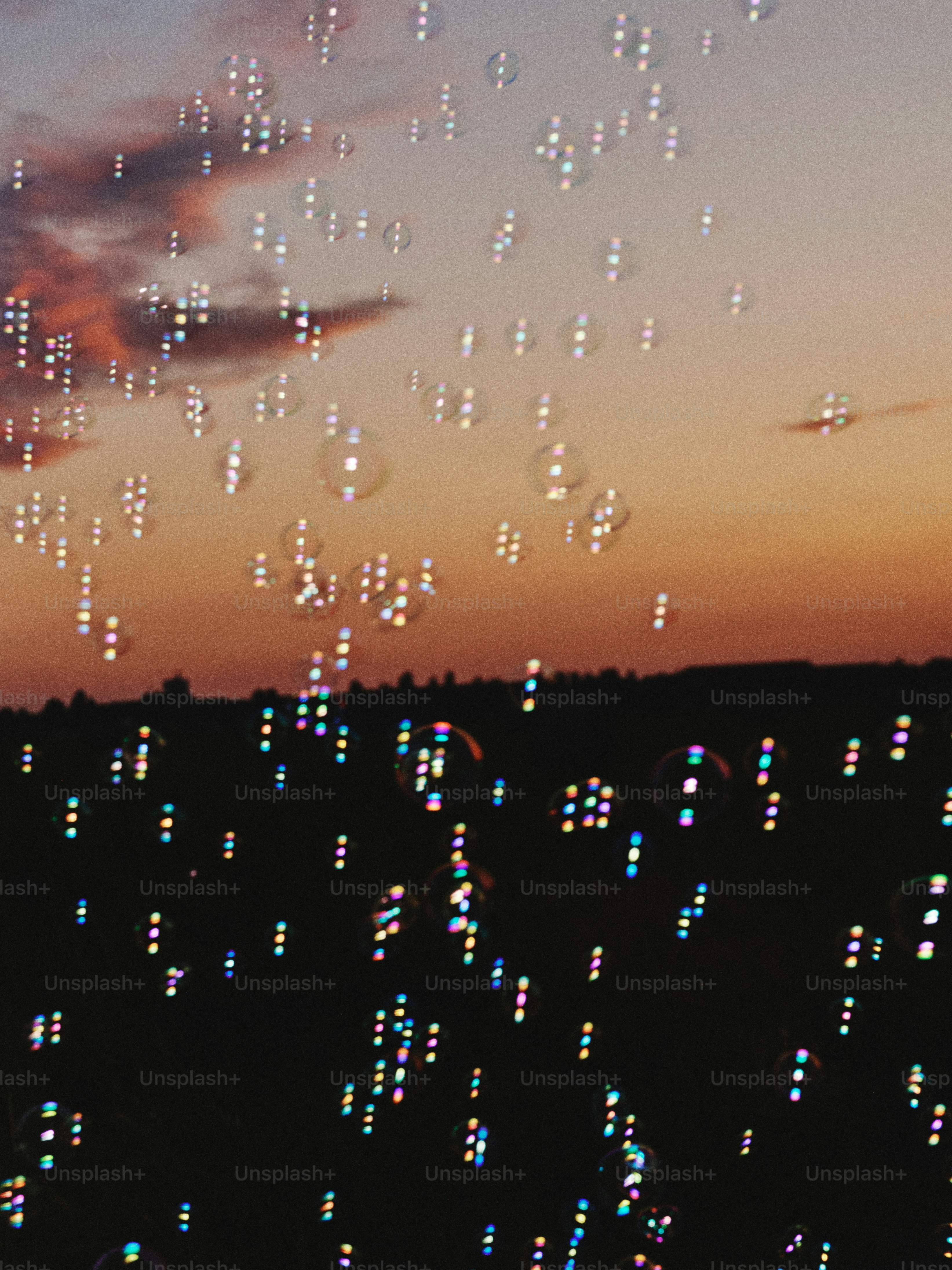 a sky filled with lots of bubbles next to a sunset