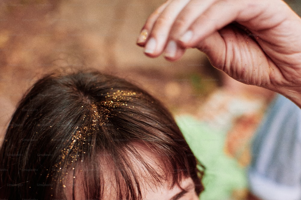 un gros plan sur les cheveux d’une femme avec des taches d’or dessus