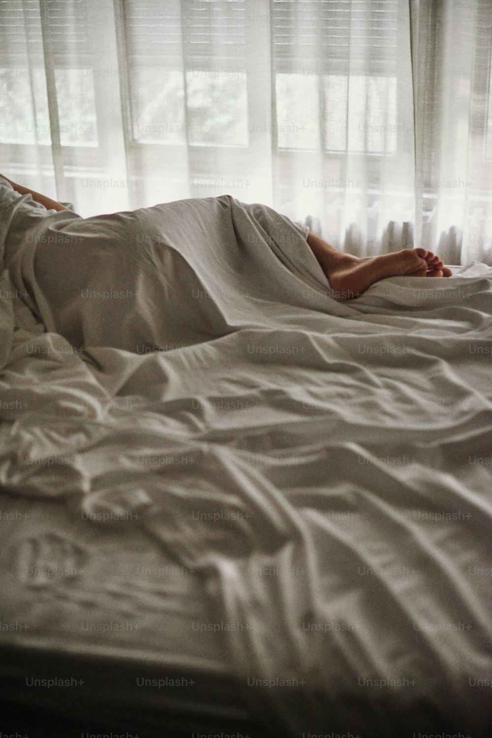 une personne allongée dans un lit avec des draps blancs