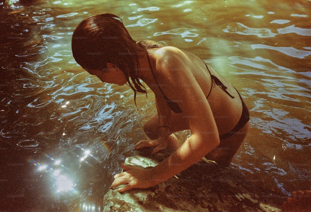 a woman in a bikini standing in a body of water