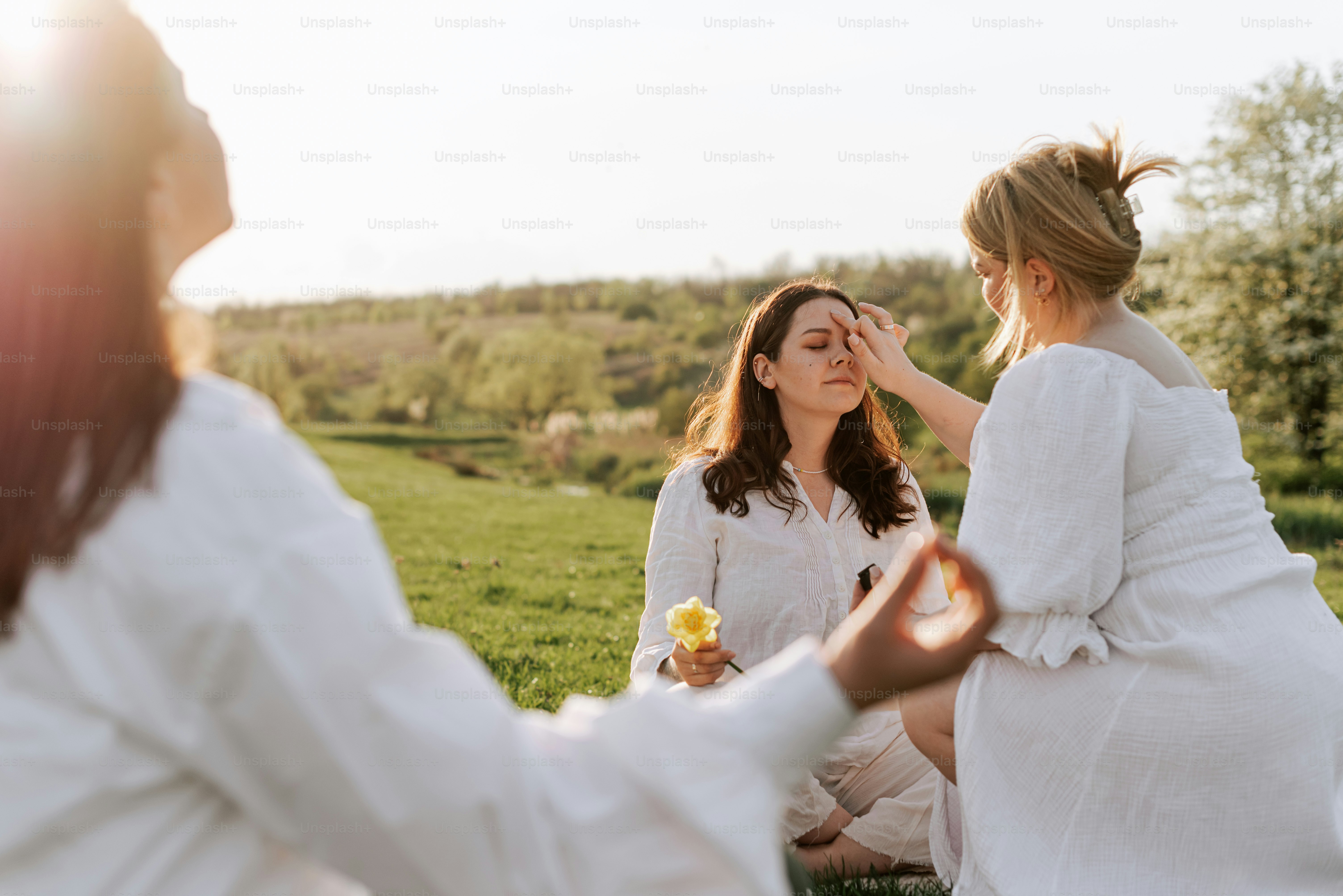 a couple of women sitting on top of a lush green field