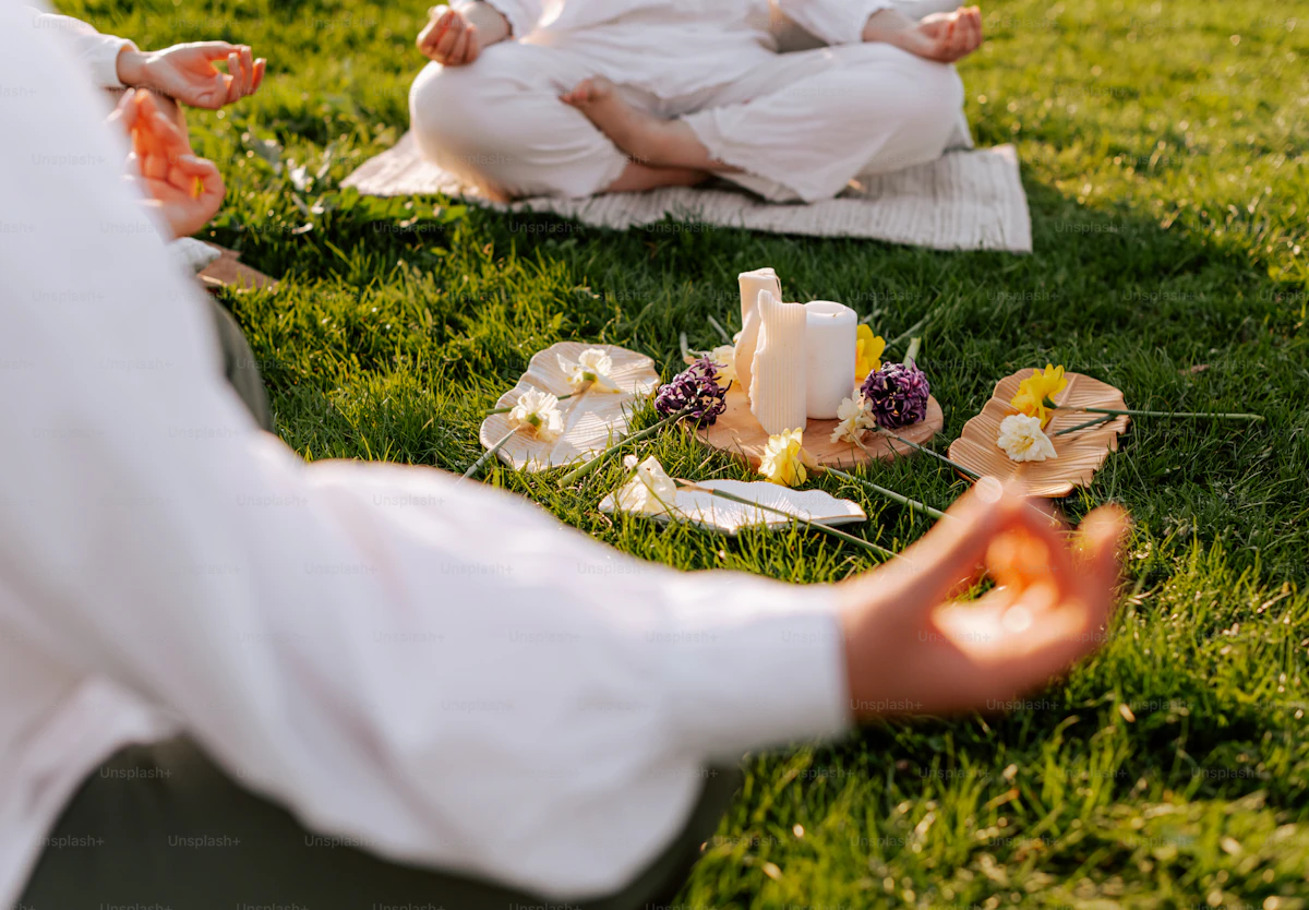 people meditating in a circle on green grass with candles and flowers