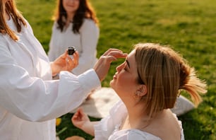 a woman getting her make up done by another woman