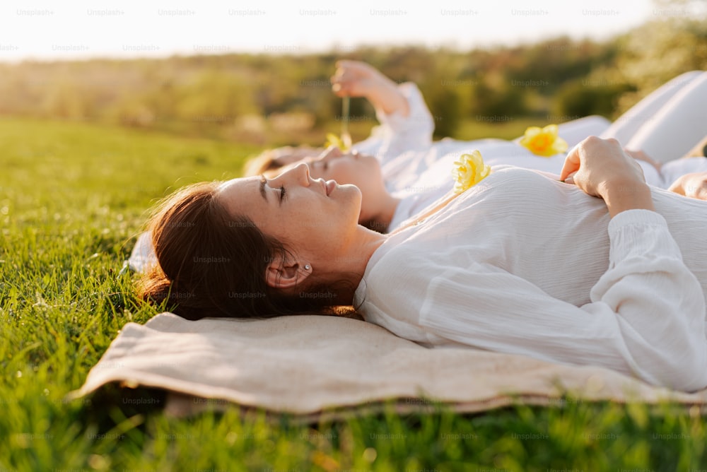 uma mulher deitada na grama com uma flor na mão