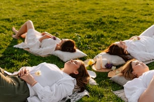 a group of women laying on top of a lush green field