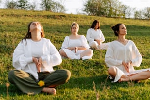 a group of women sitting on top of a lush green field