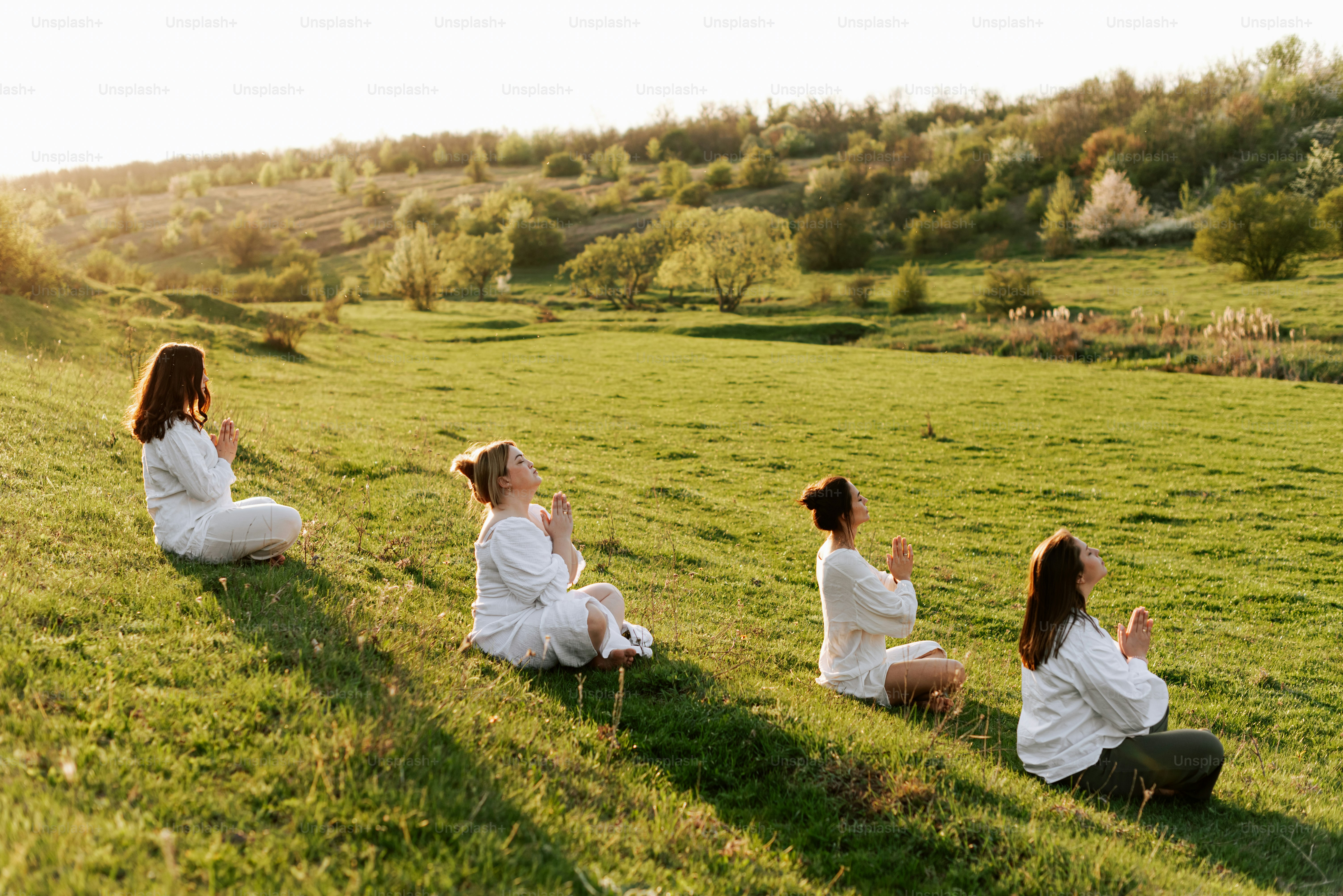 a group of women sitting on top of a lush green field