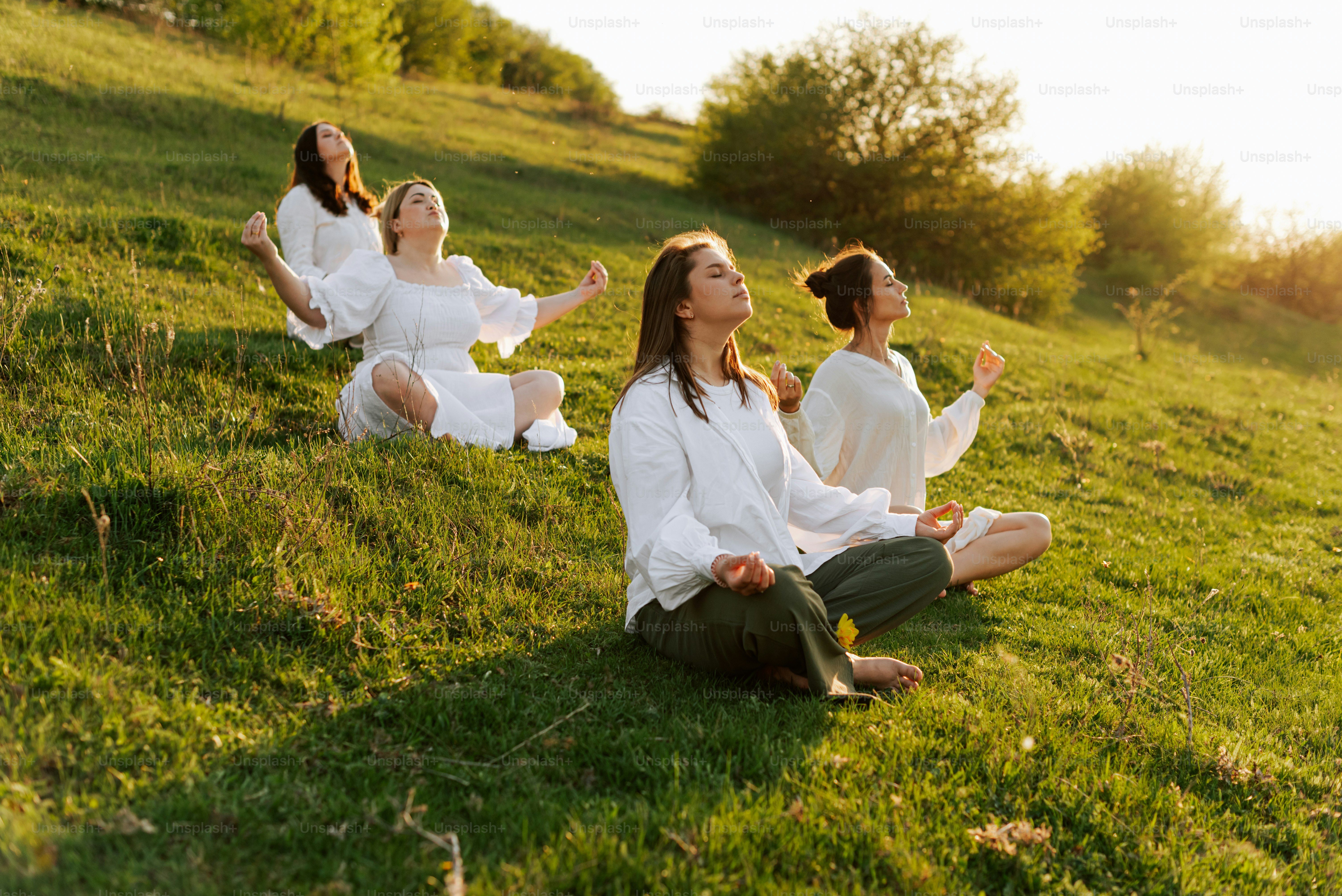 a group of women sitting on top of a lush green field