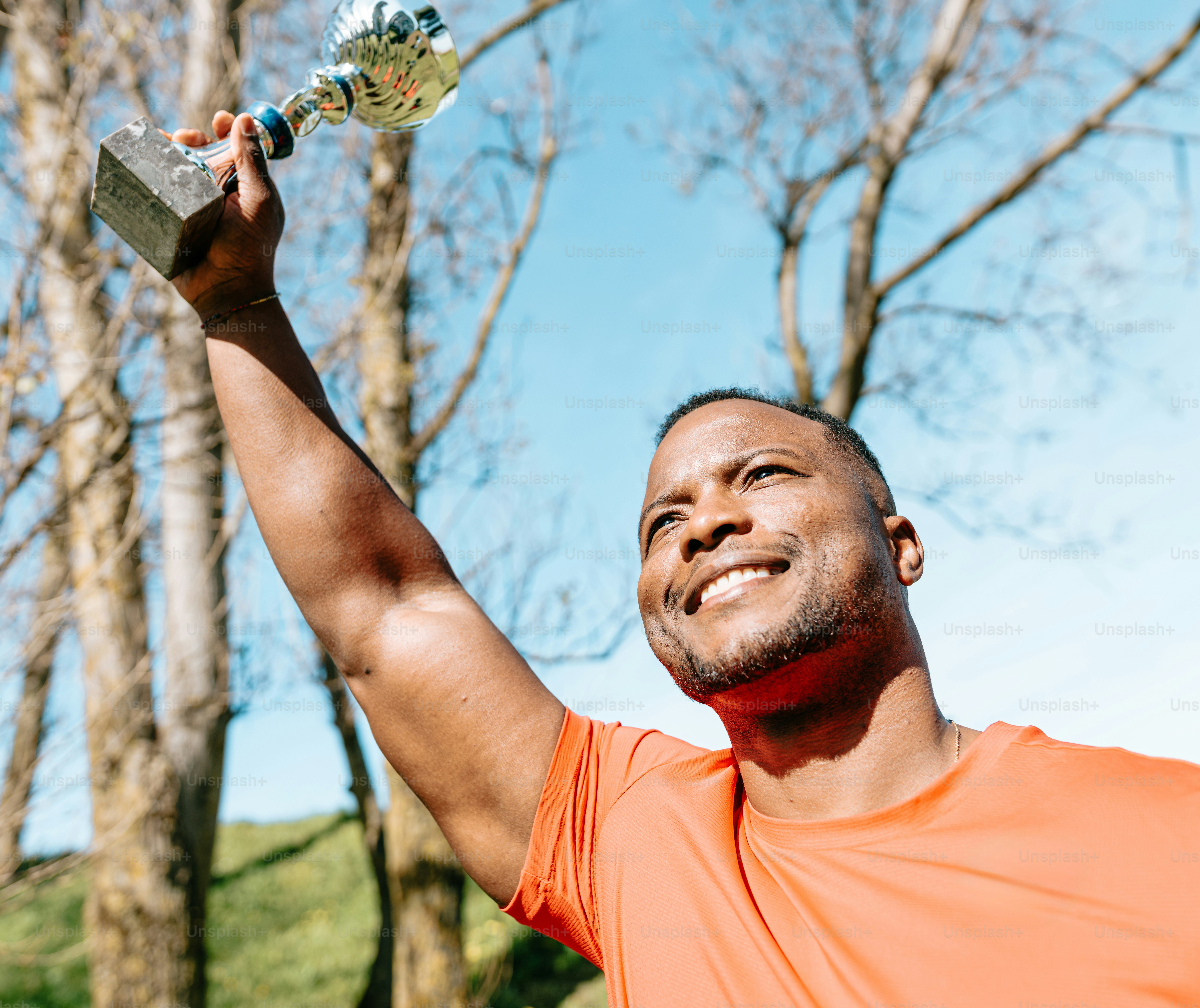 um homem de camisa laranja segurando um objeto prateado