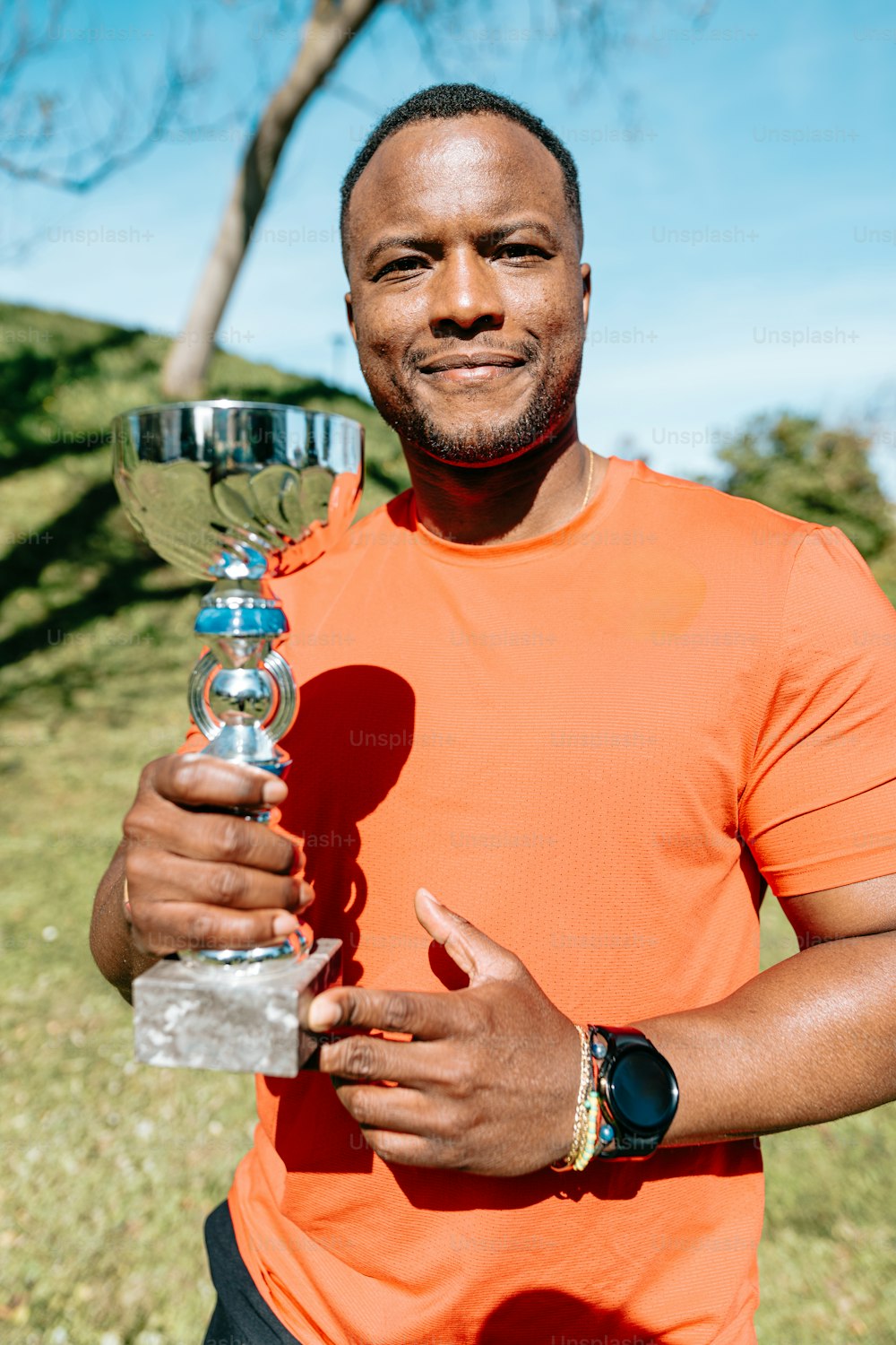 a man in an orange shirt holding a trophy
