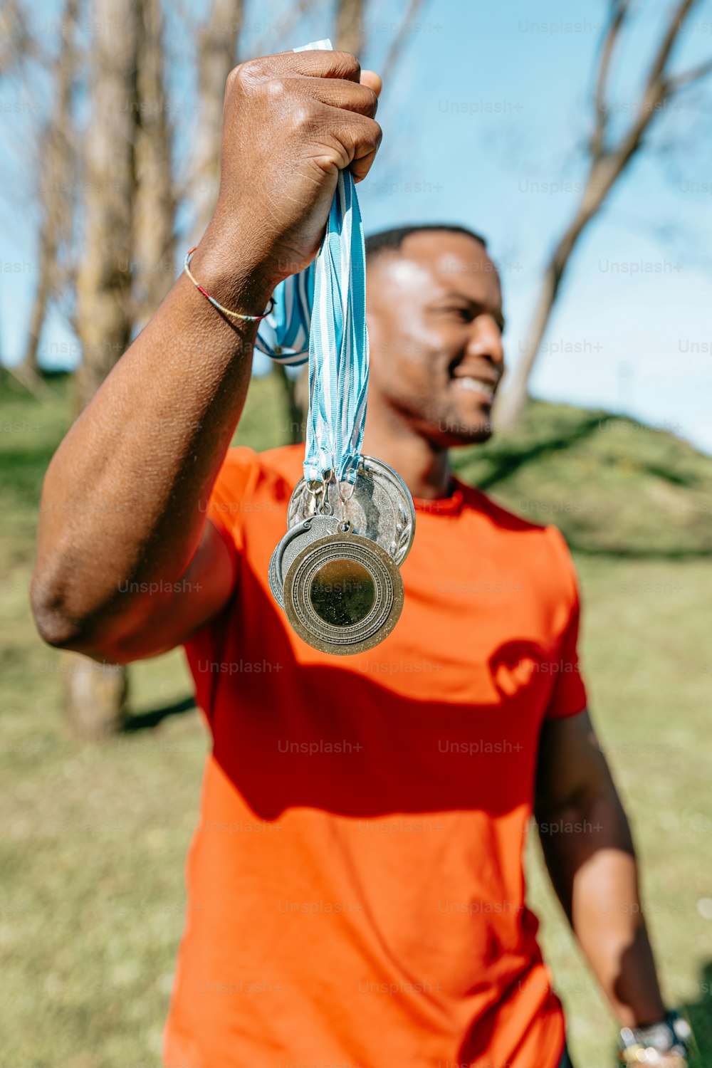 a man in an orange shirt holding up a medal