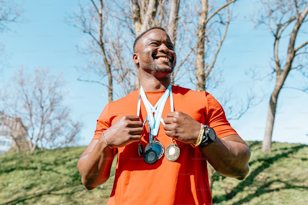 a man in an orange shirt holding two medals