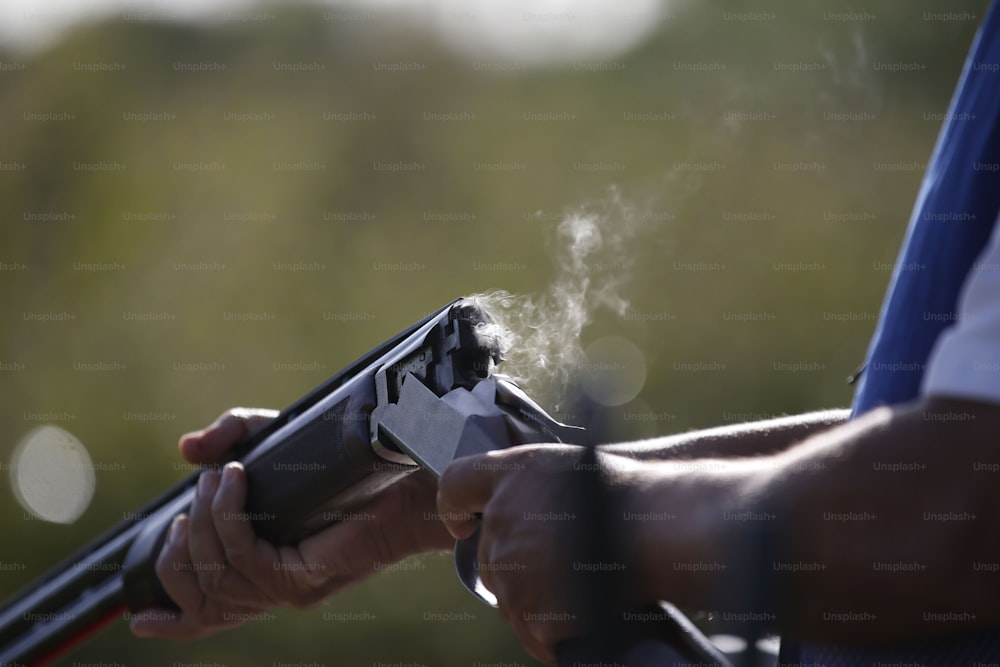 une personne tenant une arme à feu d’où s’échappe de la fumée ;
