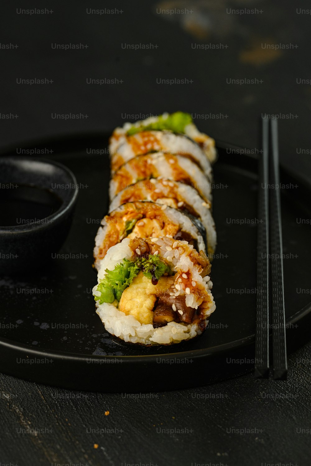 a black plate topped with sushi and chopsticks