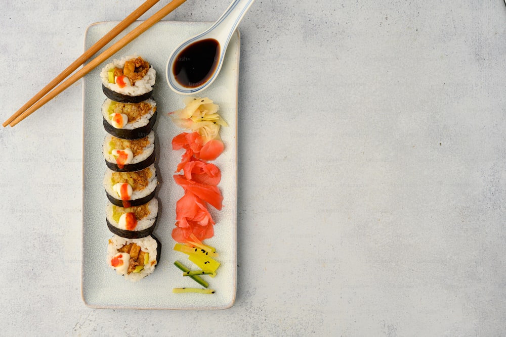 a white plate topped with sushi and chopsticks