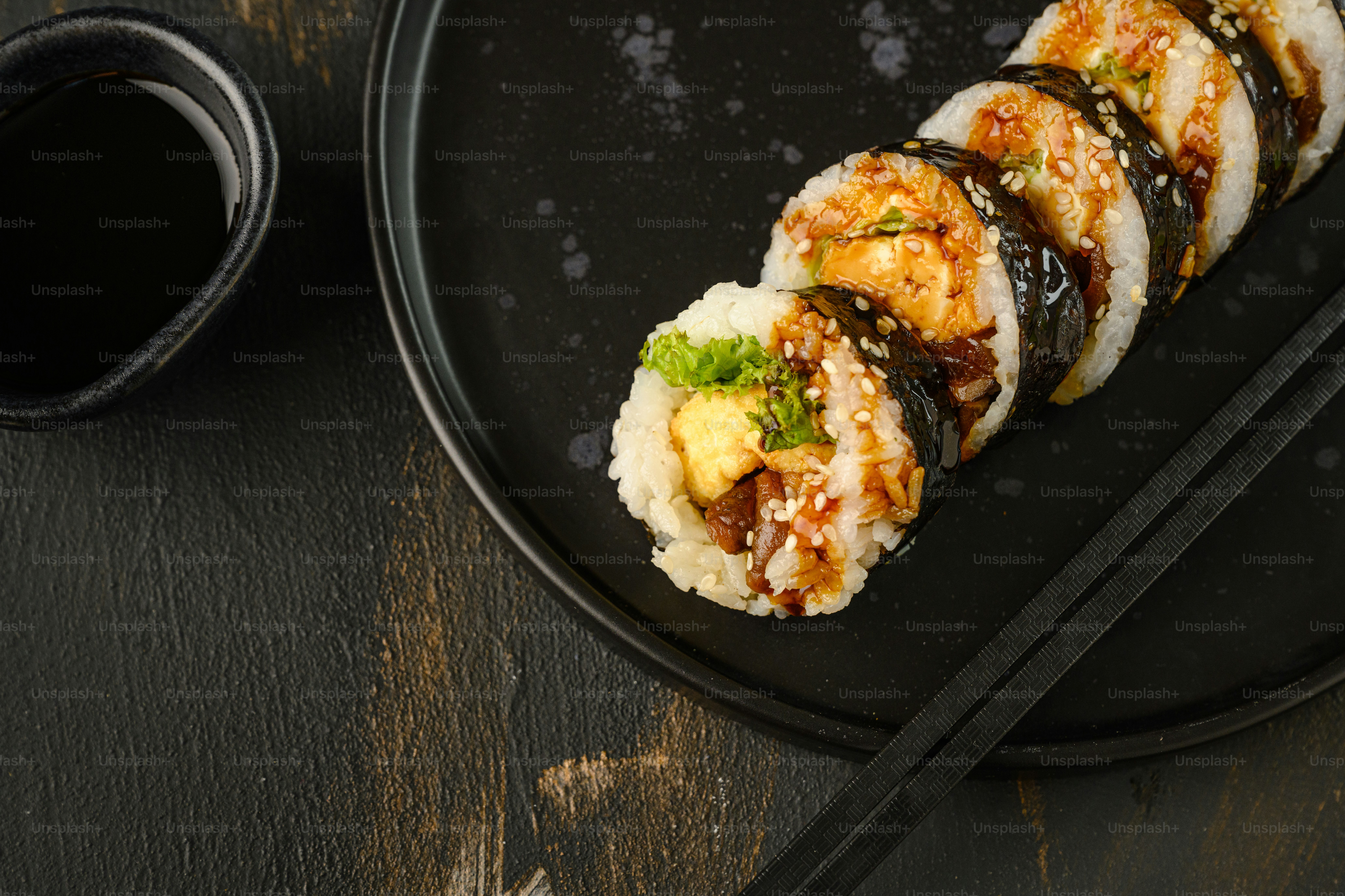 a black plate topped with sushi and chopsticks