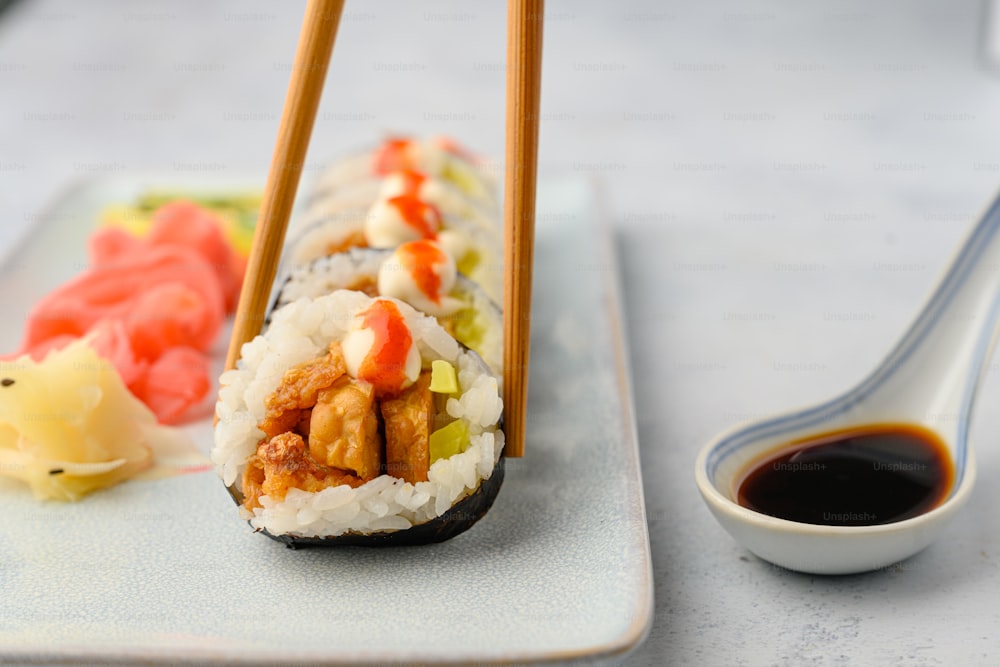 a plate of sushi with chopsticks and sauce