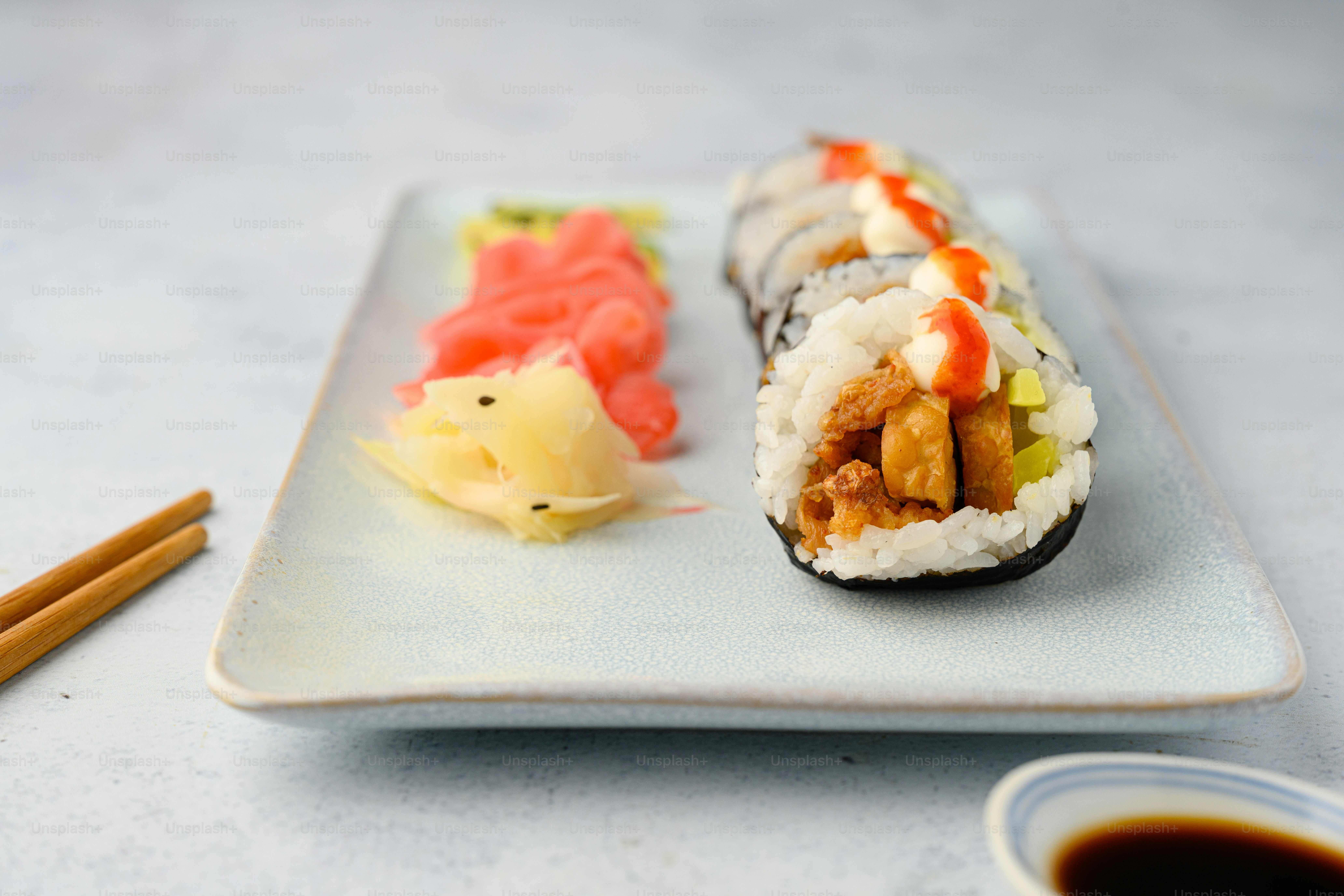 Un plato de sushi y palillos sobre una mesa