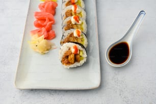 un plato blanco cubierto con sushi junto a una cuchara