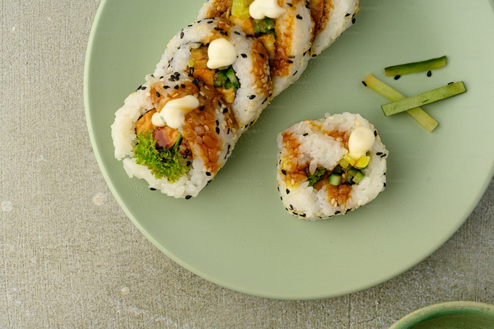 a green plate topped with sushi and vegetables