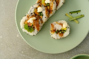a green plate topped with sushi and vegetables