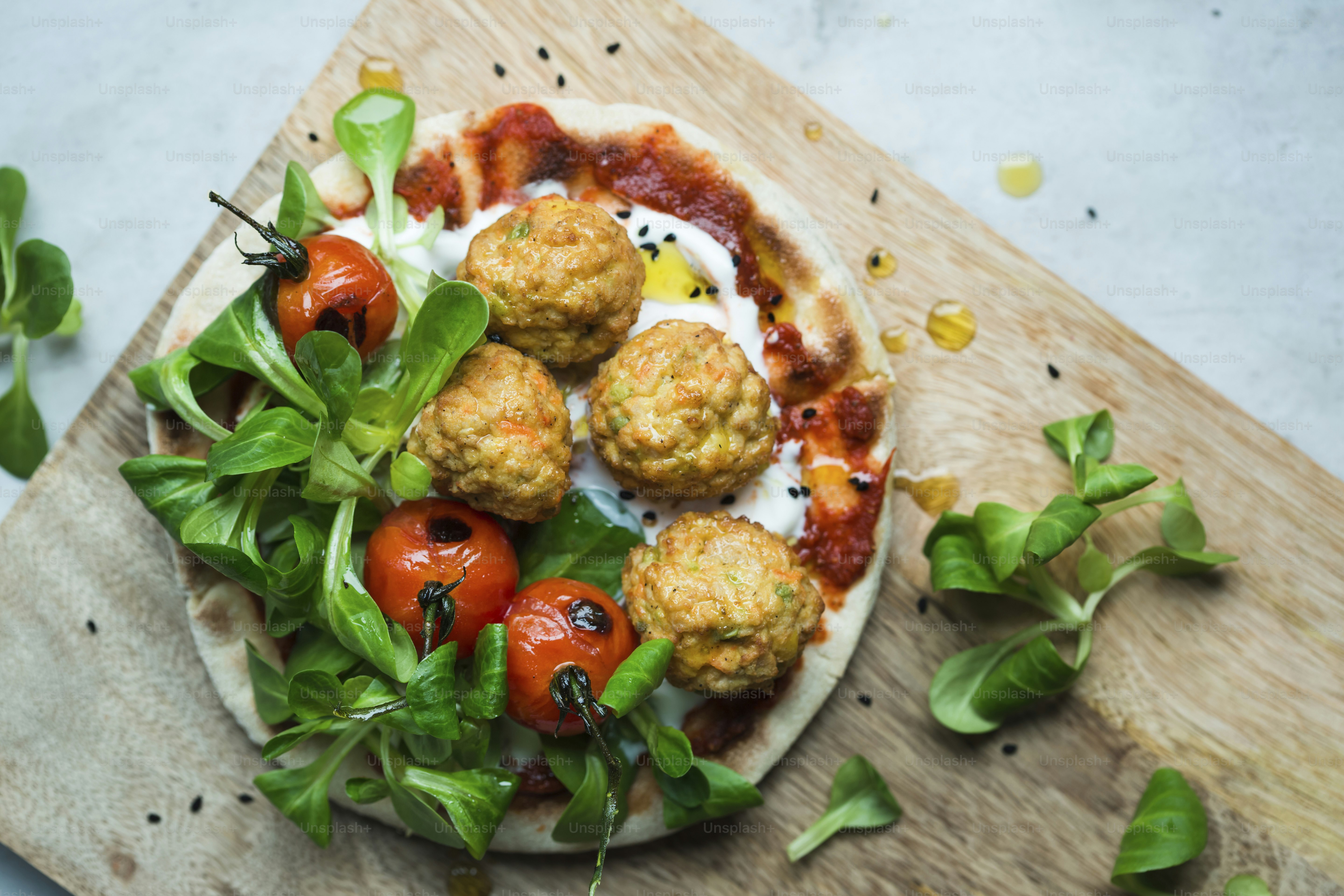 ein Teller mit Fleischbällchen und Gemüse auf einem Schneidebrett