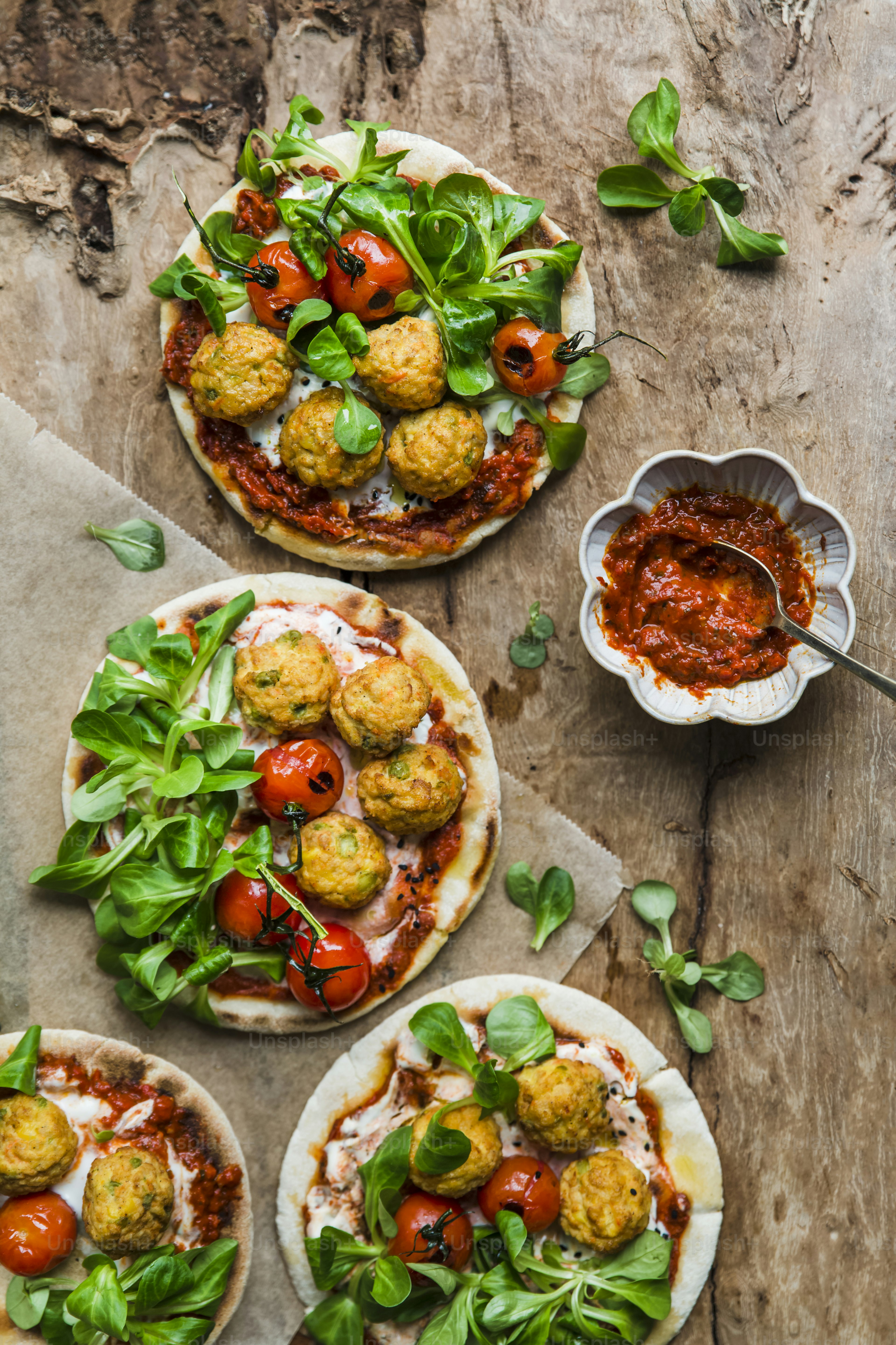 a table topped with three pizzas covered in meatballs