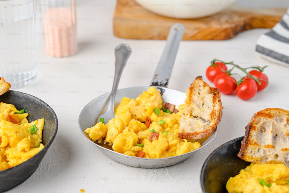 two bowls of scrambled eggs and toast on a table