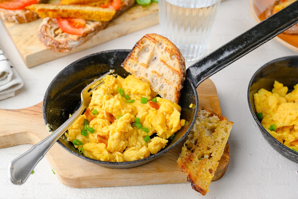 a pan of scrambled eggs with a slice of toast