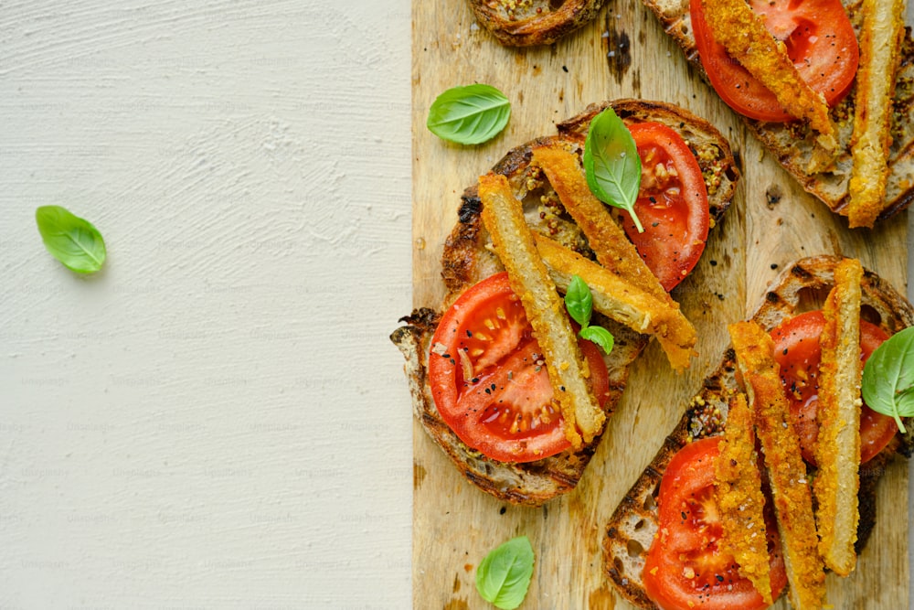 une planche à découper en bois garnie de sandwichs recouverts de tomates