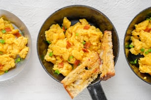three pans filled with scrambled eggs and toast
