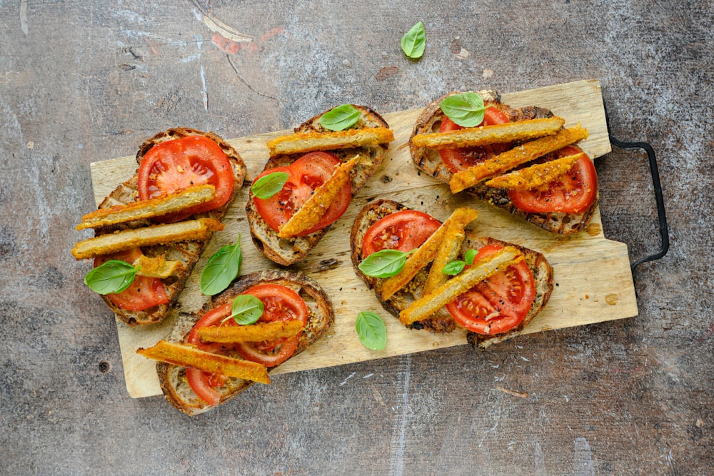 a wooden cutting board topped with sliced tomatoes and french fries