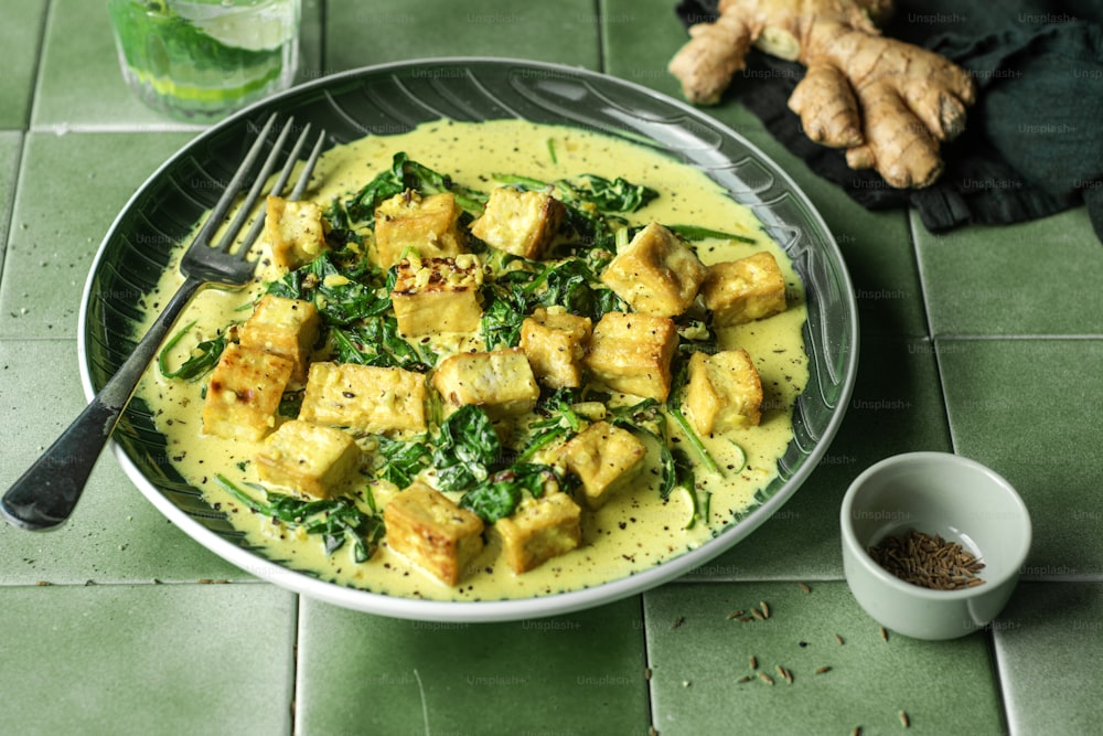 a plate of tofu and spinach with a glass of water