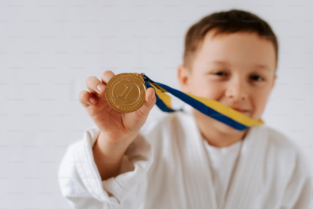 a young boy holding up a gold medal