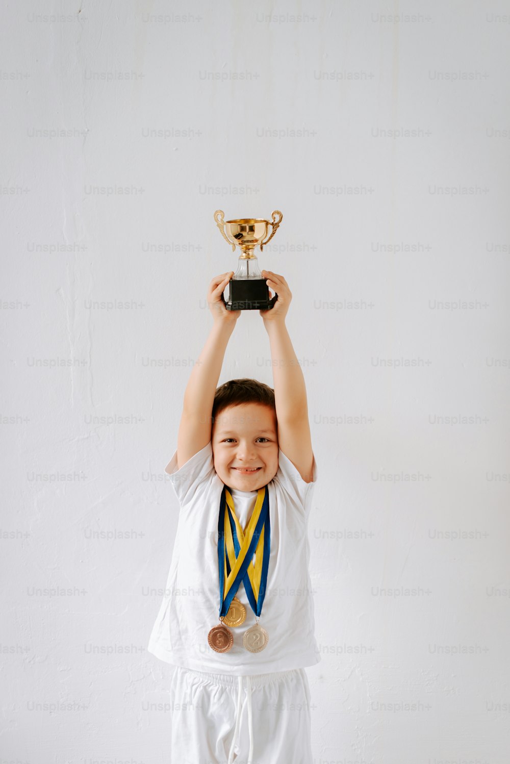 a little boy holding a trophy over his head