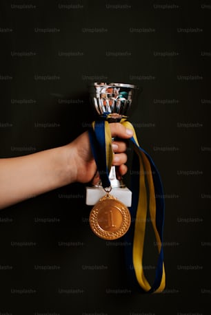 a person holding a gold medal in their hand