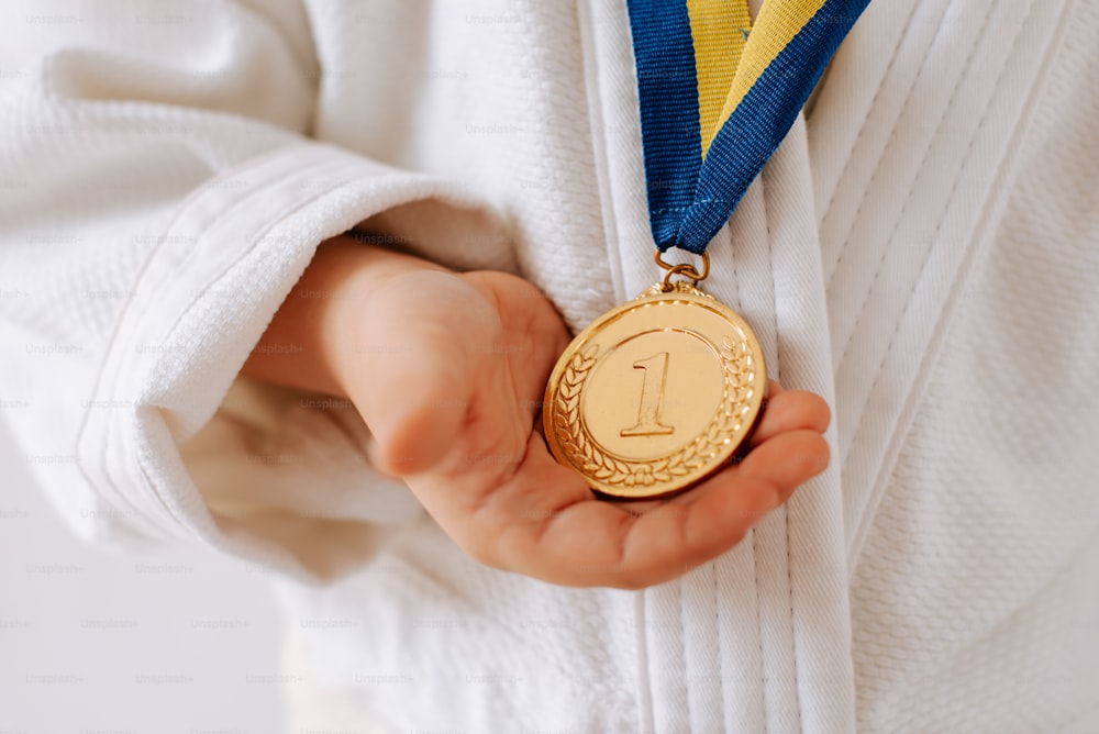 a person holding a gold medal in their hands