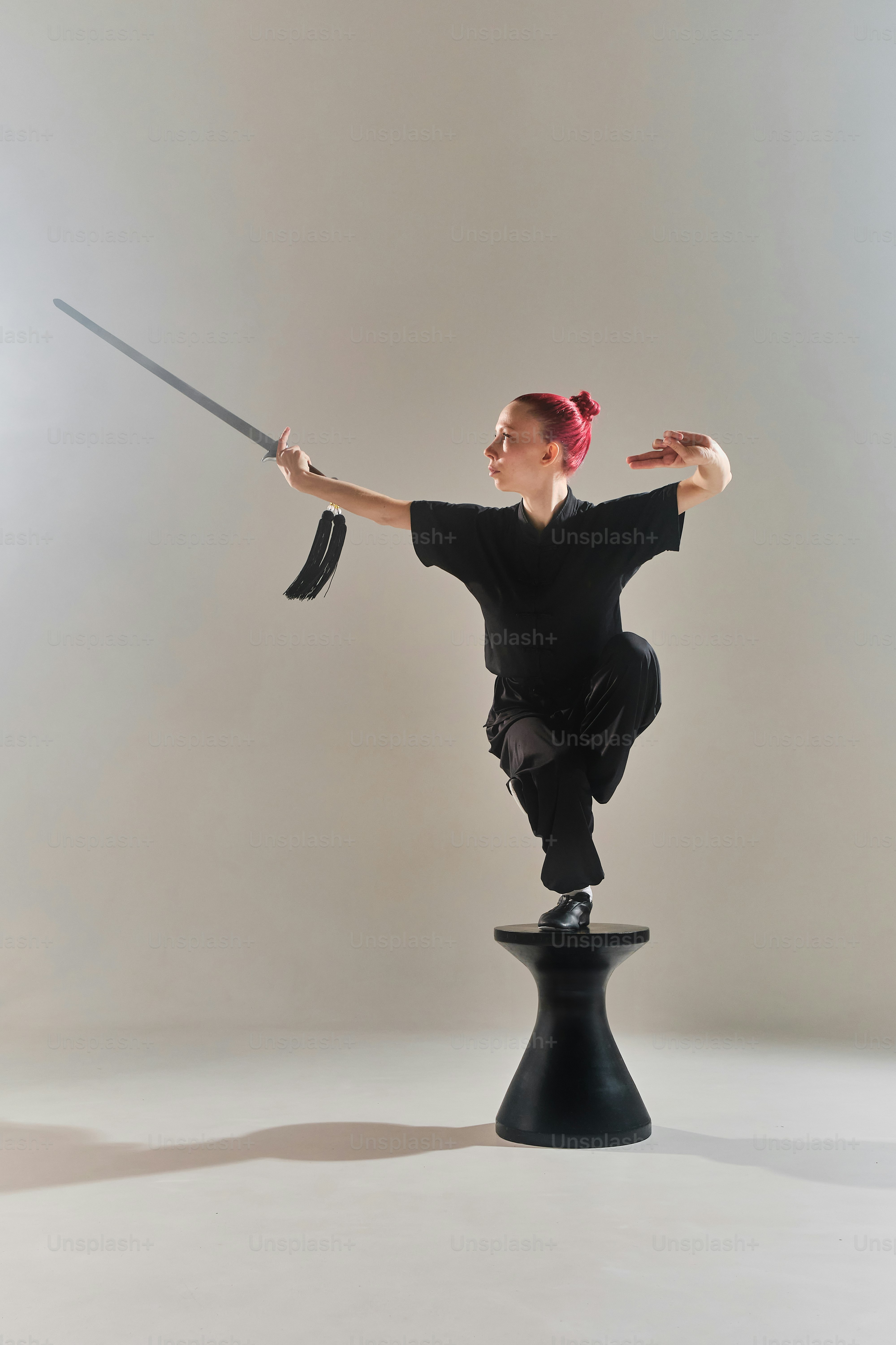 a woman in a black shirt is holding a sword