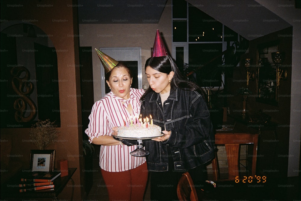a couple of women standing next to each other holding a cake