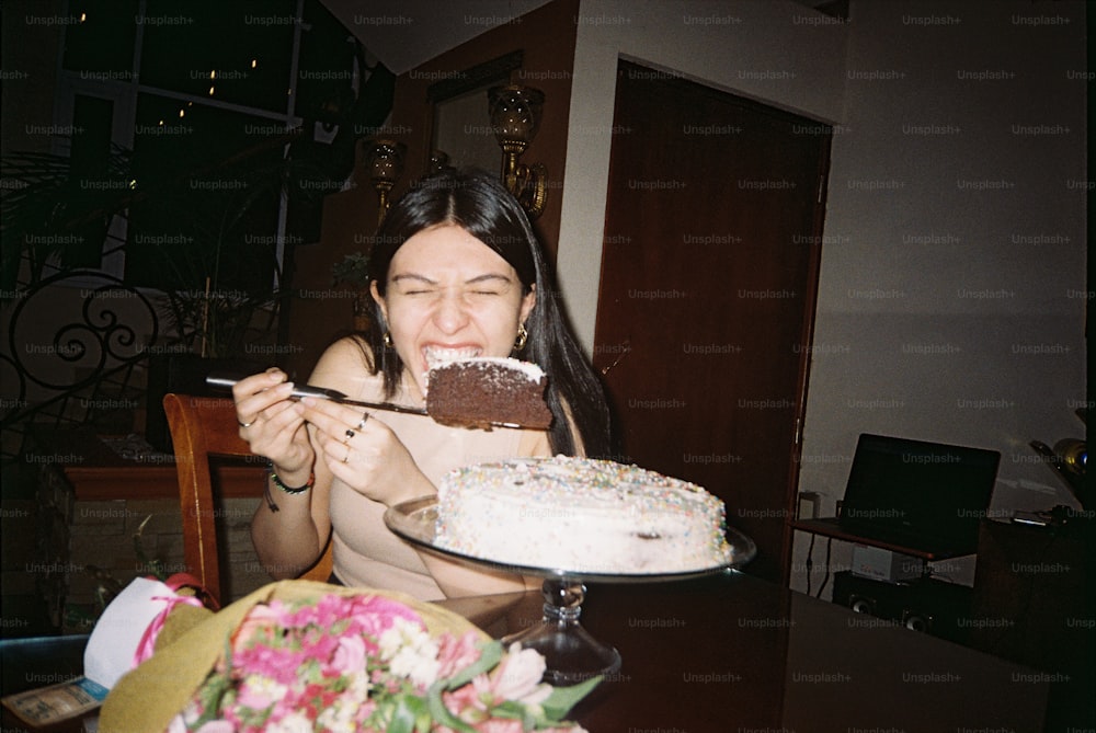 a woman sitting at a table with a plate of cake