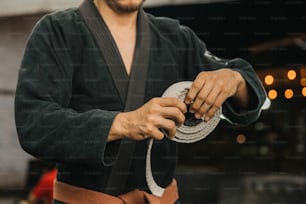um homem em um quimono está segurando uma corda