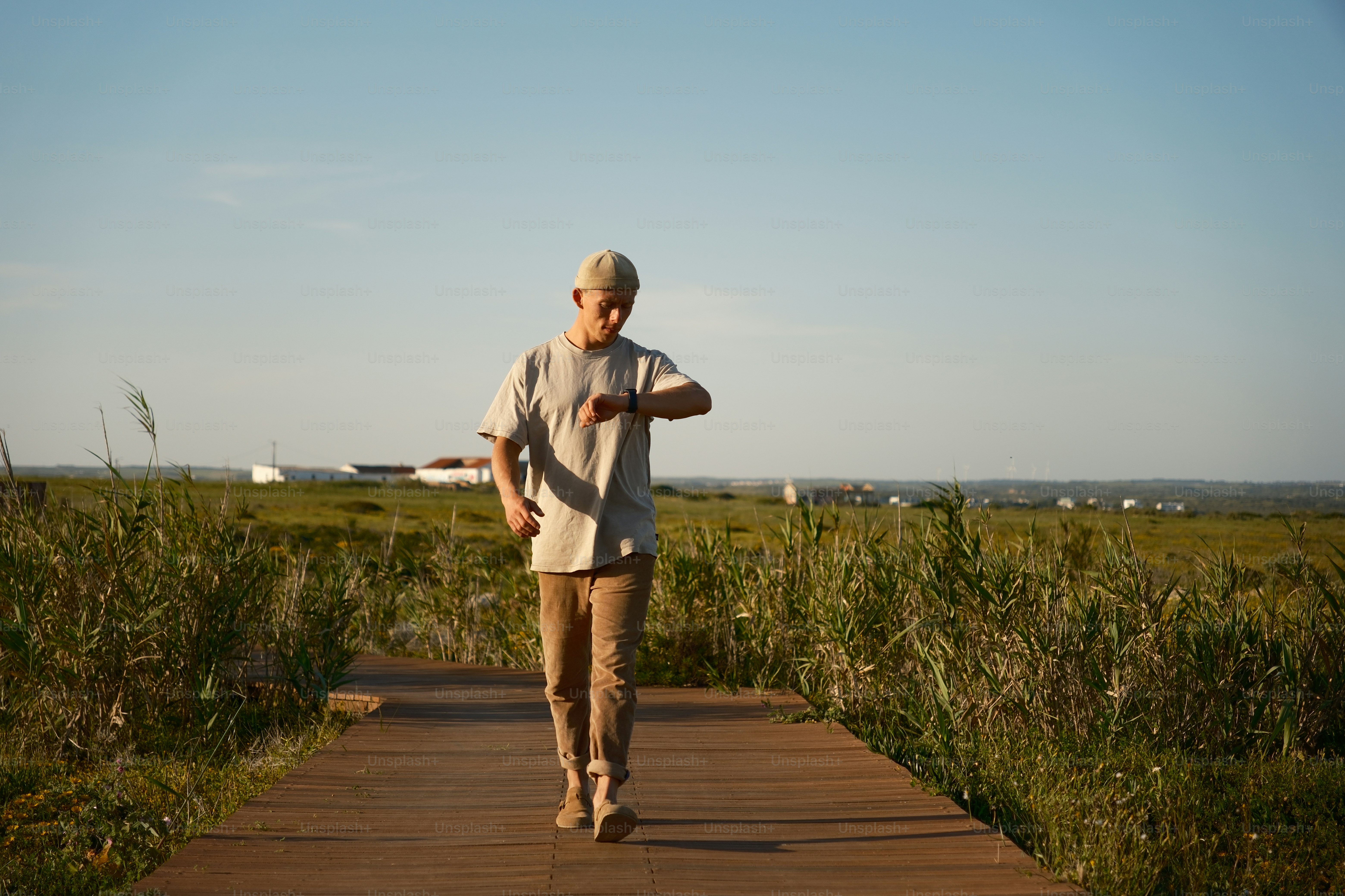 a man walking down a wooden walkway in a field