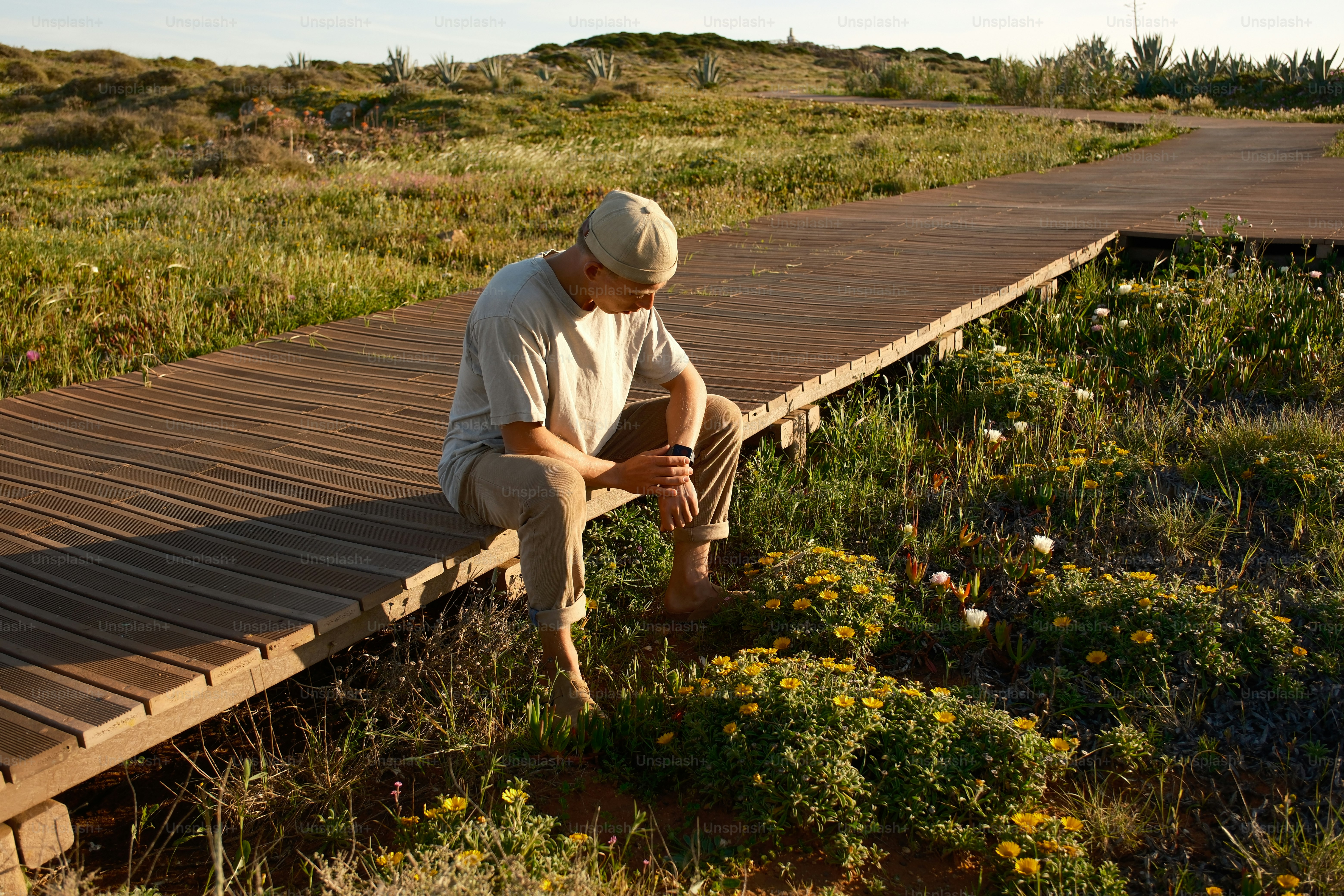 a man sitting on a wooden bridge in a field